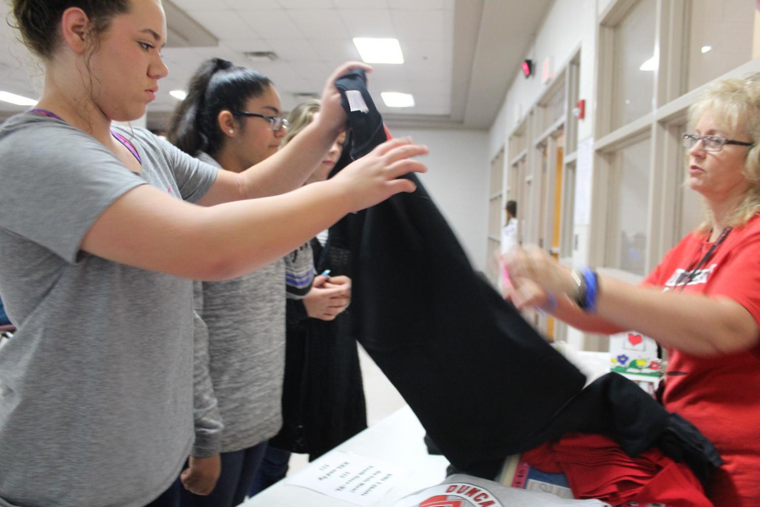 Sixth-grade science teacher Jeanna Russell sells T-shirts during club sign-ups Friday.