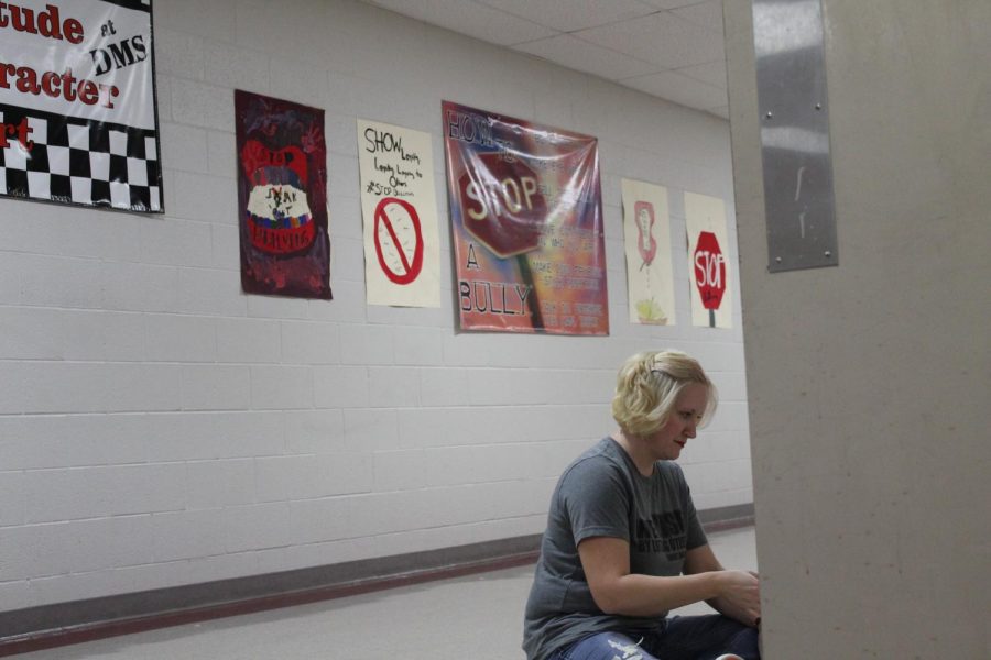 Art teacher Melissa Mayo hangs up anti-bullying posters in the elective hallway.