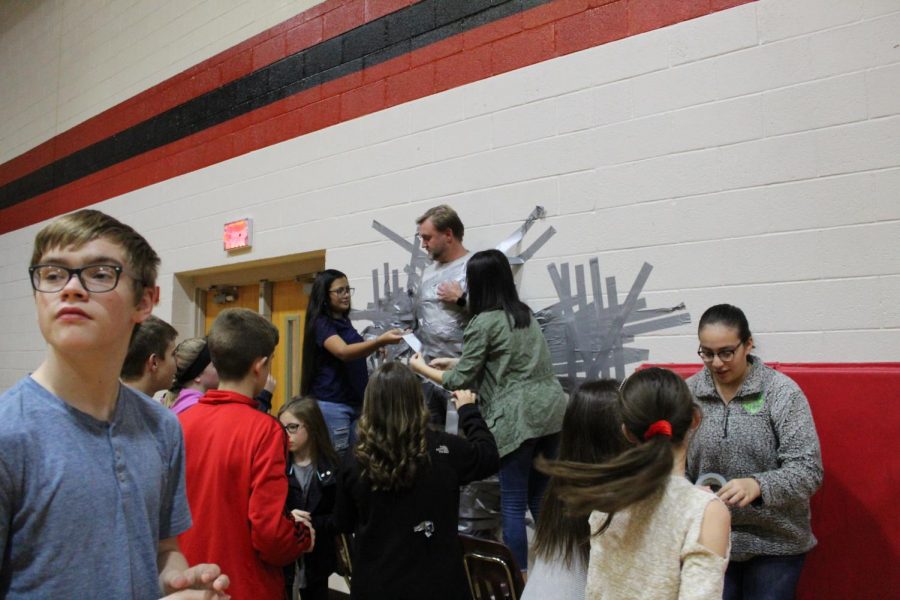 Michael Quinlan, seventh-grader, participates with other Student Council members as they tape counselor Bubba Clark to the gym wall.