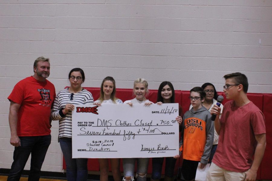 Jaxon Santos talks to Duncan Middle School students as the student council present at check to Bubba Clark for the schools clothes closet.