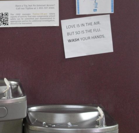 A sign above the water fountains in the eighth-grade hall remind students about the flu.