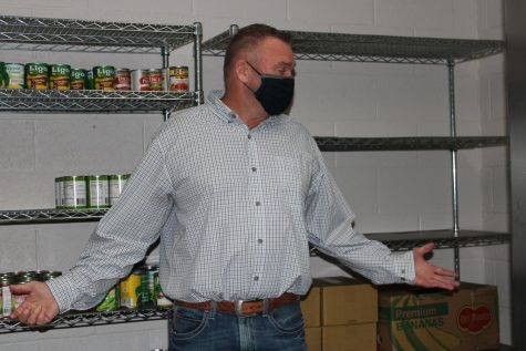 Counselor Bubba Clark shows off the empty shelves in the Duncan Middle School food pantry.