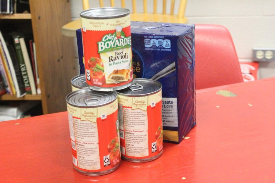 three cans and a box of macaroni that was donated to the canned food drive