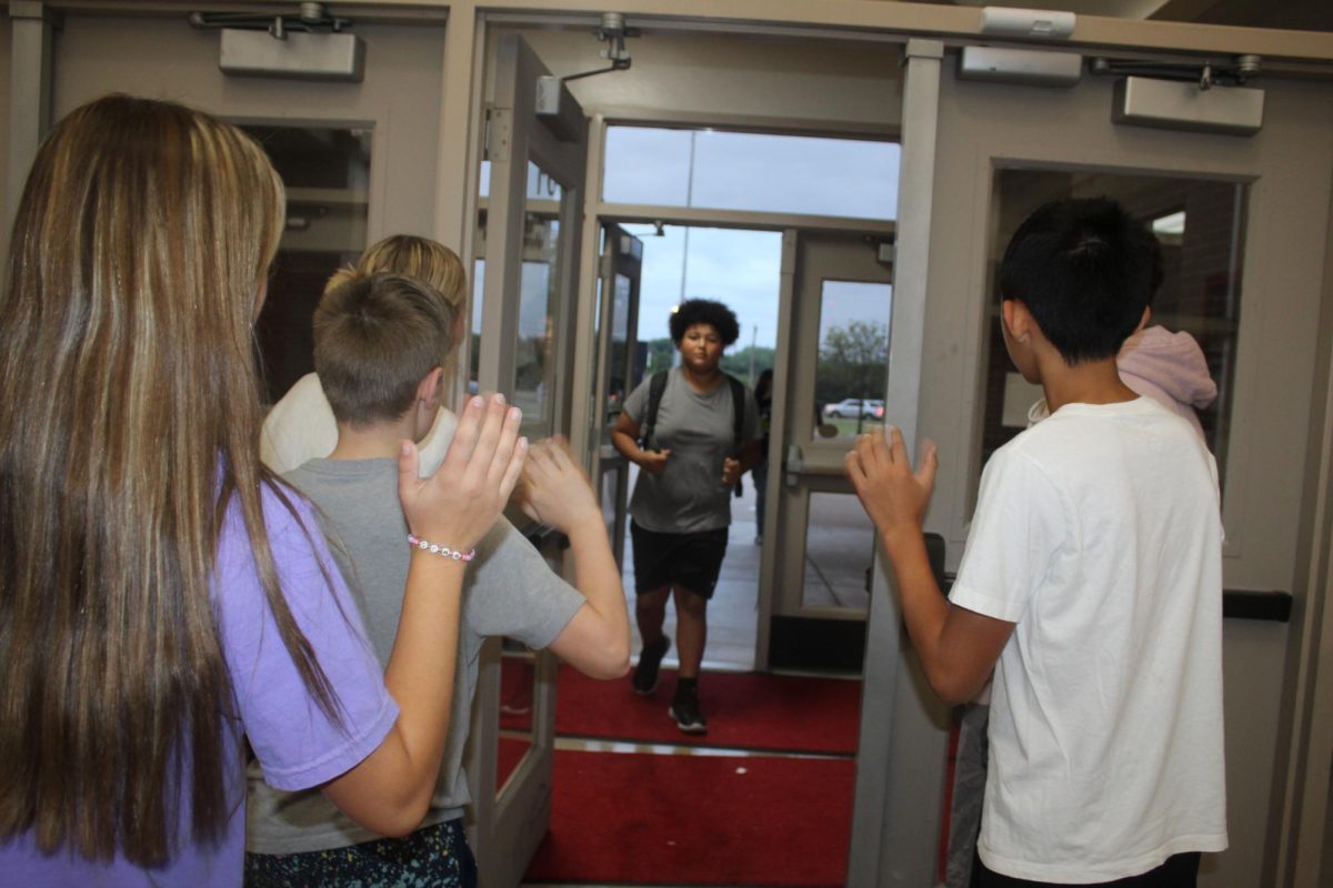 Jaheim Walker is greeted by golf and yearbook students. Different groups are stepping up to be door greeters each week in the mornings before school.