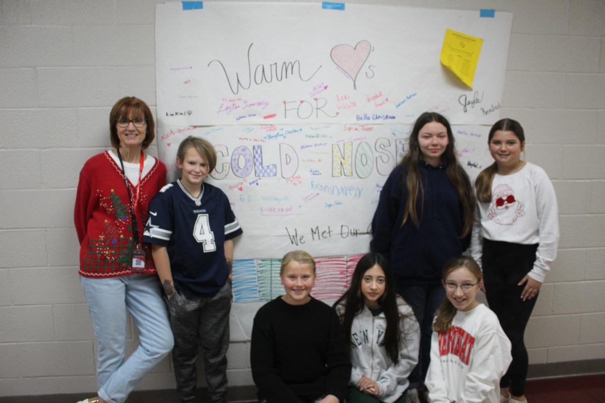 Sixth-grade math teacher Julie Leippe poses with sixth-graders in front of their gratitude project poster. The sixth-grade gratitude project collected items for the Stephens County Humane Society.
