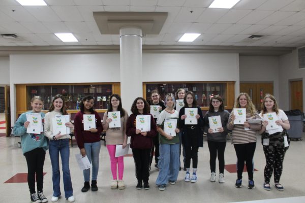 Musical cast poses for a photo with scripts for Frog and Toad.