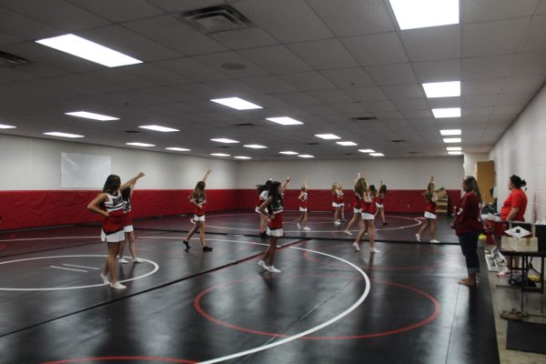 DMS cheerleaders practice a cheer and dance routine in the wrestling room.