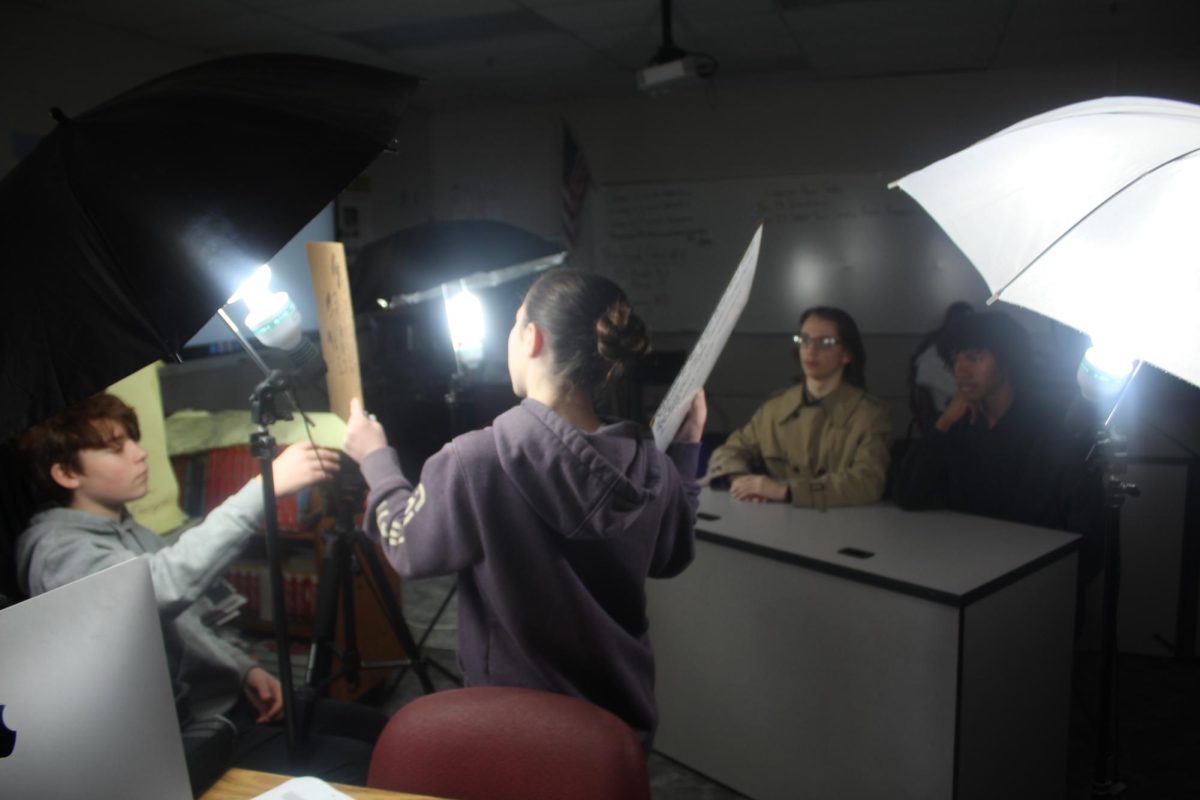 Wyatt Patterson and Ellie Edwards work behind the scenes of the video update, while Thor Beck and Daniel DeGreef prepare to share information.