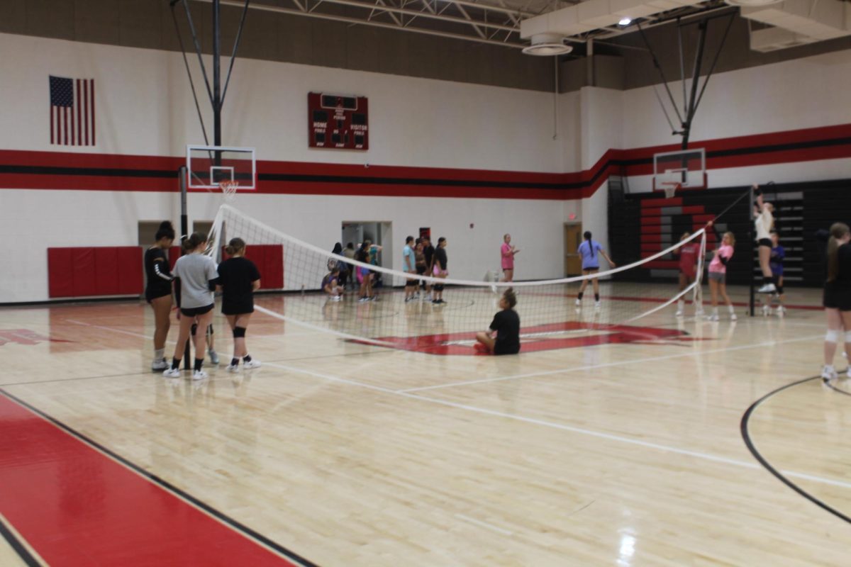 Volleyball players set up a net during practice earlier this week.