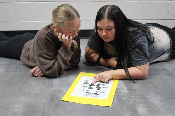 Caylin Copeland, left, and Jaiden Ellison look at a sign, featuring the dress code.