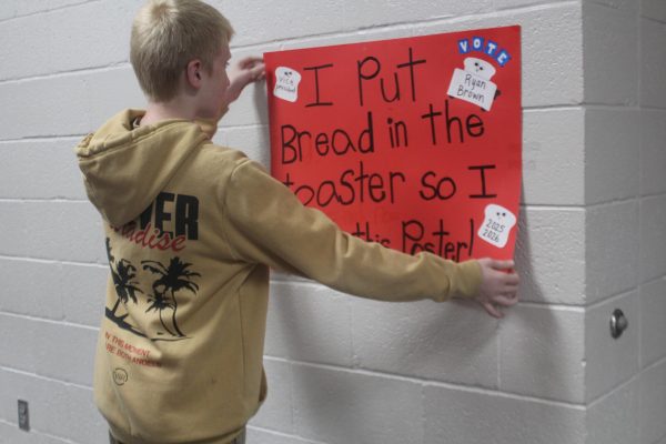 Ryan Brown hangs a poster for the NJHS officer election. Brown is running for NJHS vice president.