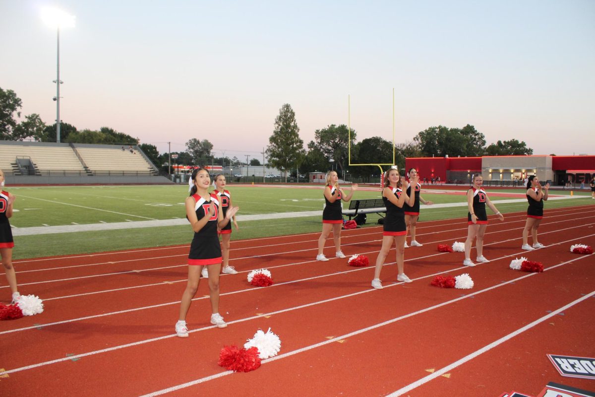 Cheerleaders cheer on the sidelines of a football game during the first semester.