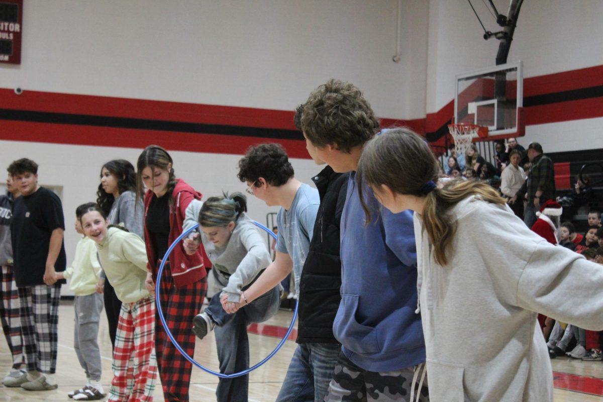 Eighth-grade students move the hula-hoop from person to person during one of the Reindeer Games.