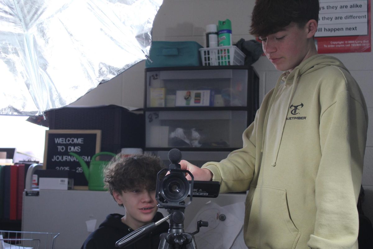 Cash McRoy and Wyatt Patterson look over the camcorder used for the video News Update.
