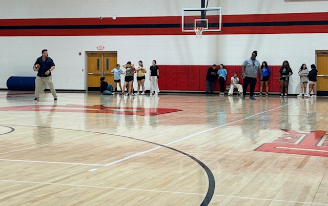 Steven Dixon demonstrates football moves, while middle school girls watch.